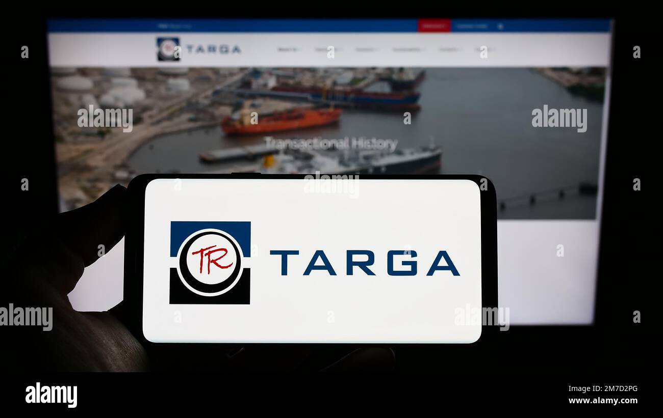 Persona in possesso di smartphone con il logo della società energetica statunitense Targa Resources Corp. Sullo schermo di fronte al sito Web. Messa a fuoco sul display del telefono. Foto Stock