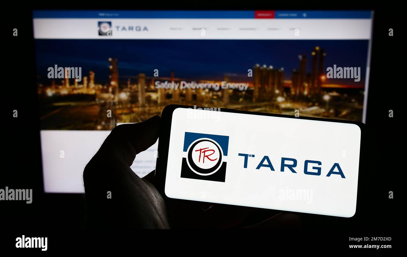 Persona che tiene il telefono cellulare con il logo della società americana energia Targa Resources Corp. Sullo schermo di fronte al sito web aziendale. Messa a fuoco sul display del telefono. Foto Stock