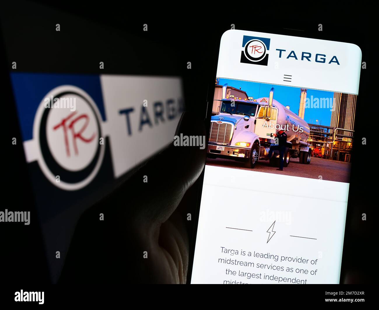 Persona in possesso di smartphone con il sito Web della società energetica americana Targa Resources Corp. Sullo schermo davanti al logo. Messa a fuoco al centro del display del telefono. Foto Stock