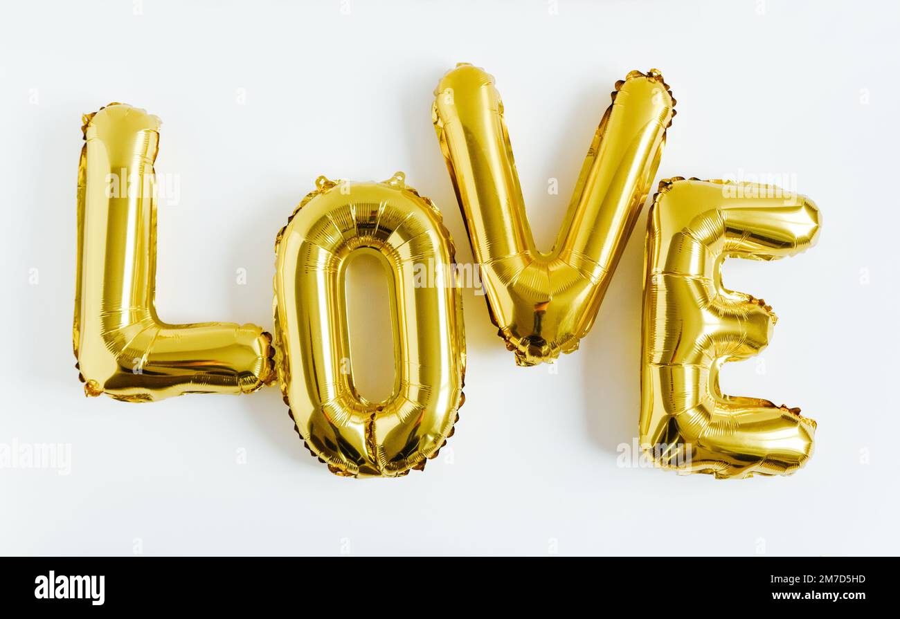 Iscrizione LOVE foil ballon dorato gonfiabile su sfondo bianco. Amore, romanticismo e San Valentino concetto. Giacitura piatta Foto Stock