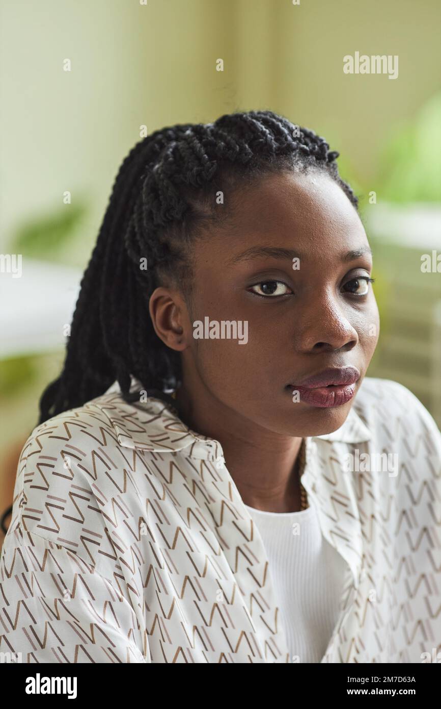 Ritratto verticale di una giovane donna nera che guarda la fotocamera in ufficio con sfondo sfocato Foto Stock