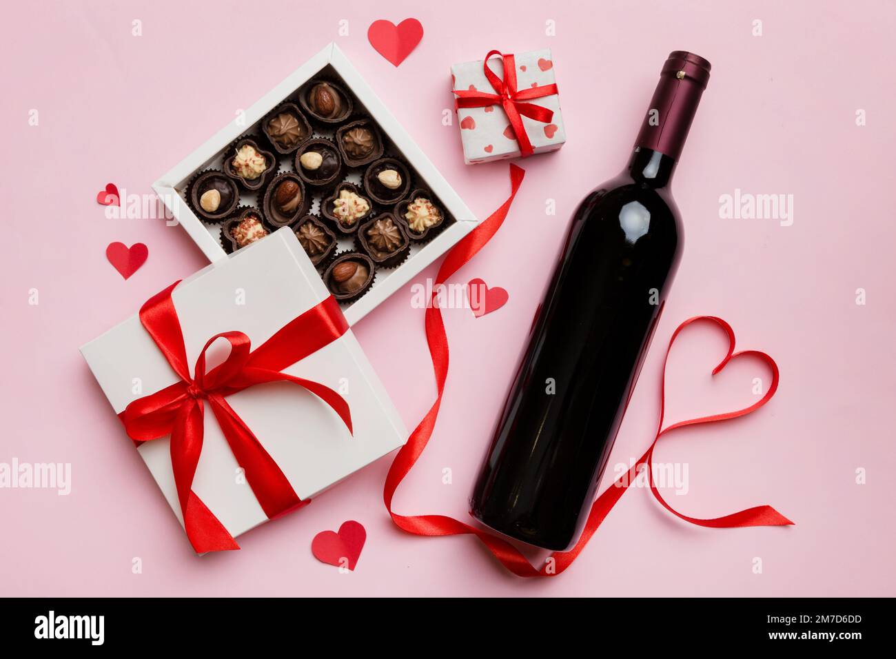 Bottiglia di vino rosso su sfondo colorato per San Valentino con regalo e  cioccolato. A forma di cuore con scatola di cioccolatini in omaggio vista  dall'alto e spazio per fotocopie Foto stock -