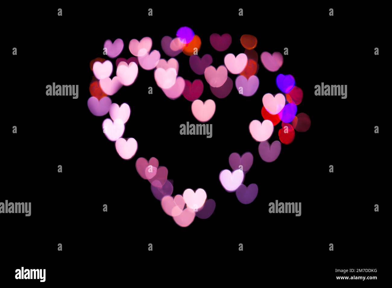 Luci bokeh rosa a forma di cuore su sfondo nero, amore e San Valentino saluti Foto Stock