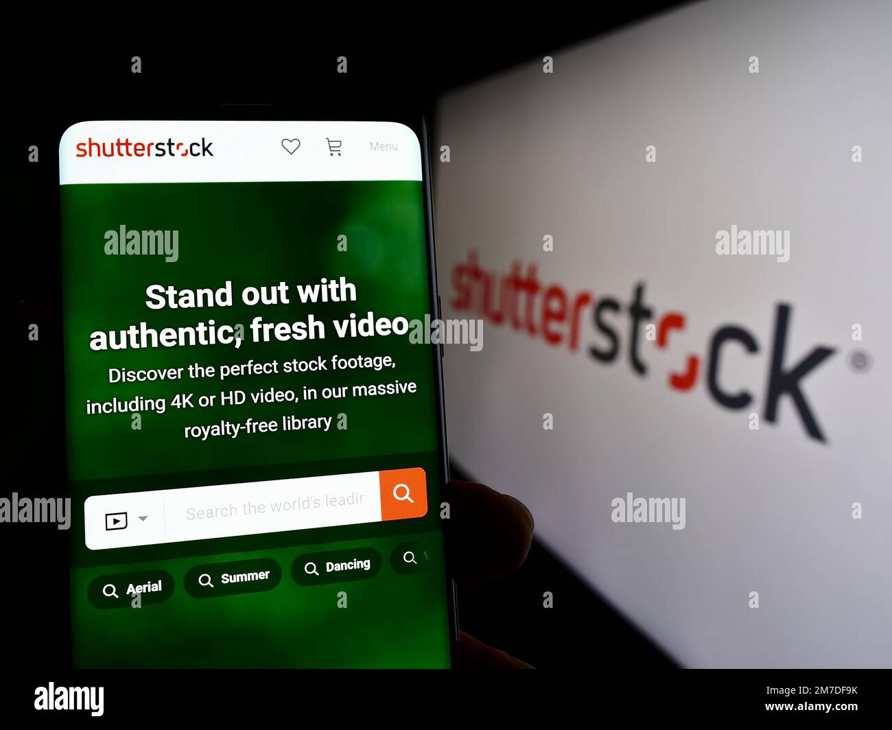 Persona che tiene in mano uno smartphone con la pagina web della società di fotografia americana Shutterstock Inc. Sullo schermo con logo. Messa a fuoco al centro del display del telefono. Foto Stock