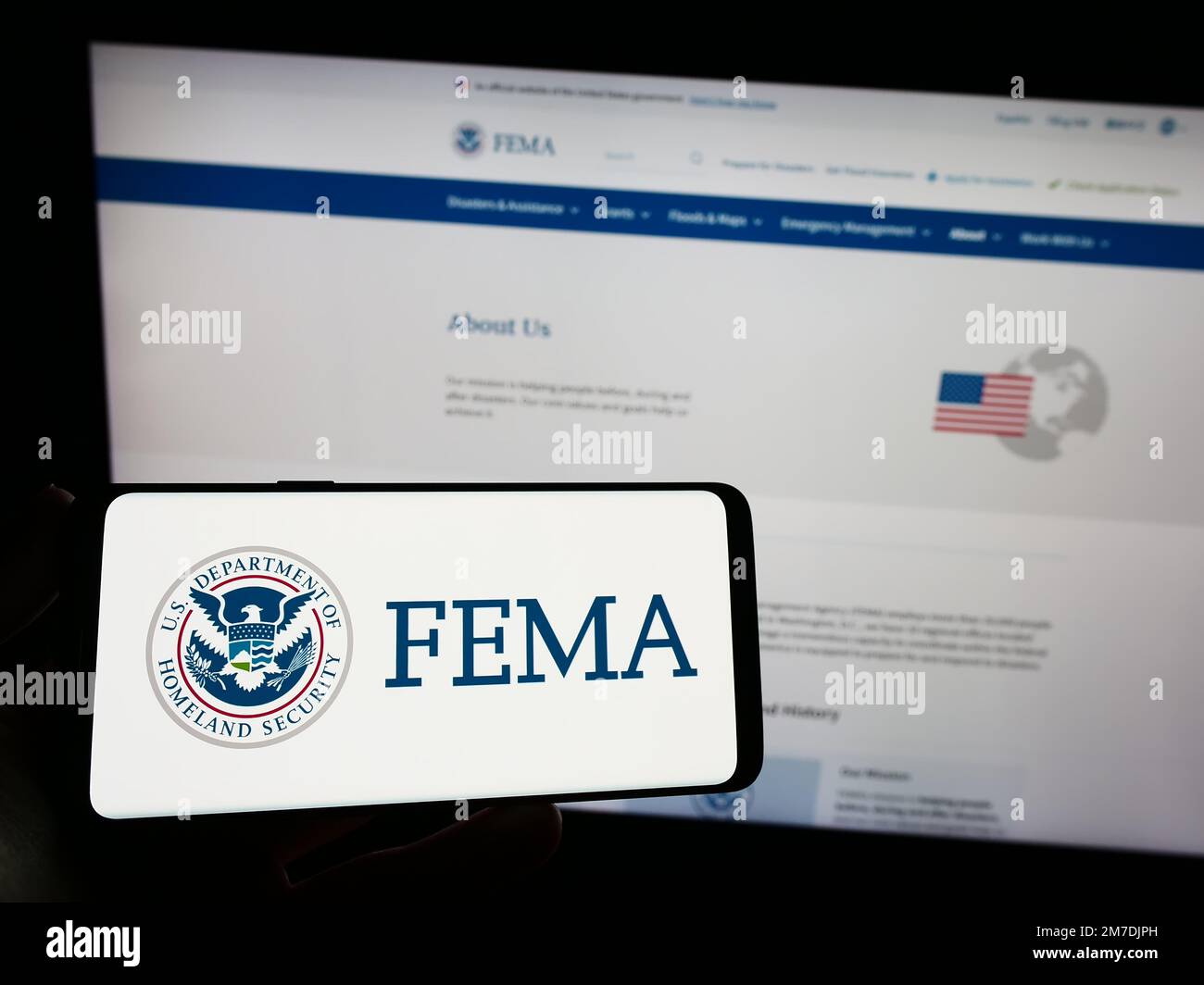 Persona che tiene lo smartphone con il sigillo della Federal Emergency Management Agency (FEMA) sullo schermo di fronte al sito Web. Messa a fuoco sul display del telefono. Foto Stock Persona che tiene lo smartphone con il sigillo della Federal Emergency Management Agency (FEMA) sullo schermo di fronte al sito Web. Messa a fuoco sul display del telefono. Foto Stock