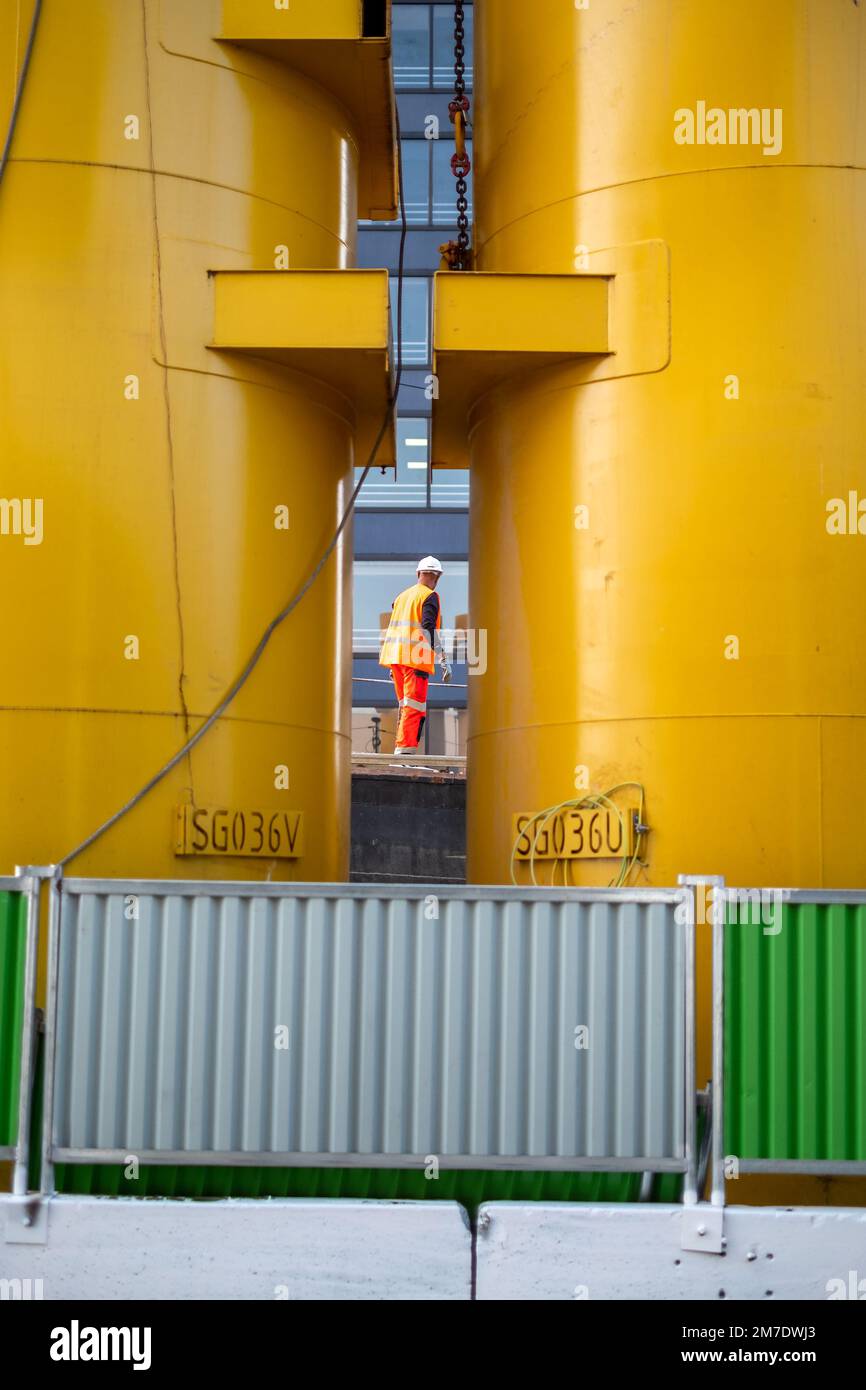Lavoratore di costruzione visto tra 2 pali di fondazione Foto Stock