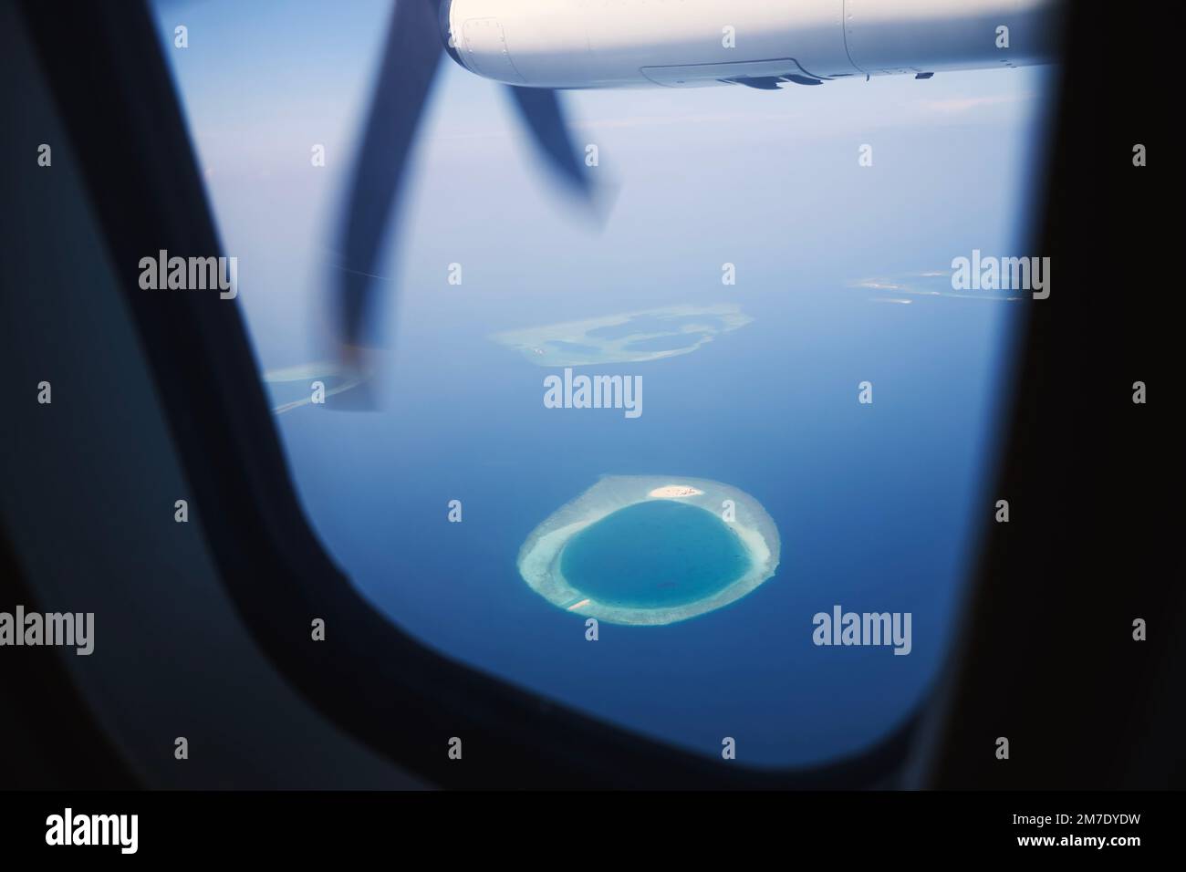 Vista dalla finestra dell'aereo turboelica alle Maldive. Oceano Indiano con bellissime isole tropicali in una idilliaca giornata di sole. Foto Stock
