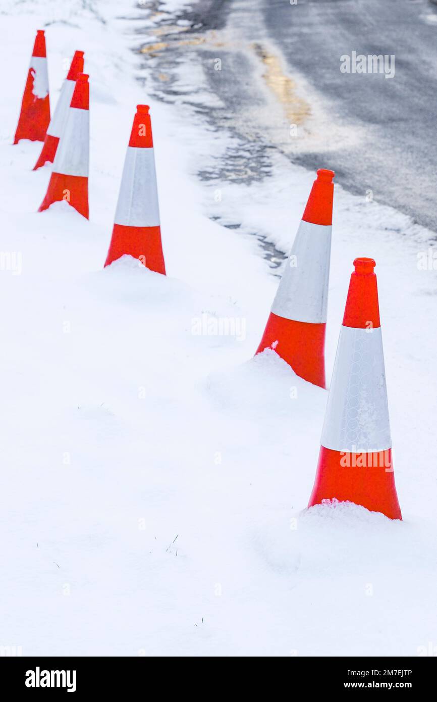 Coni di traffico almsot nascosto nella neve sul bordo di una strada di campagna. Foto Stock