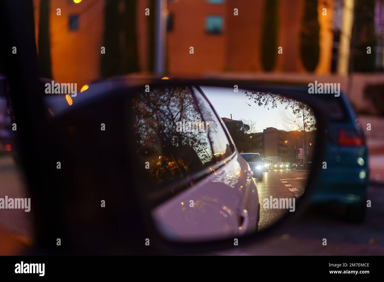 Specchietto retrovisore di un'auto di notte che riflette le luci di altri veicoli che circolano sulla strada. Foto Stock