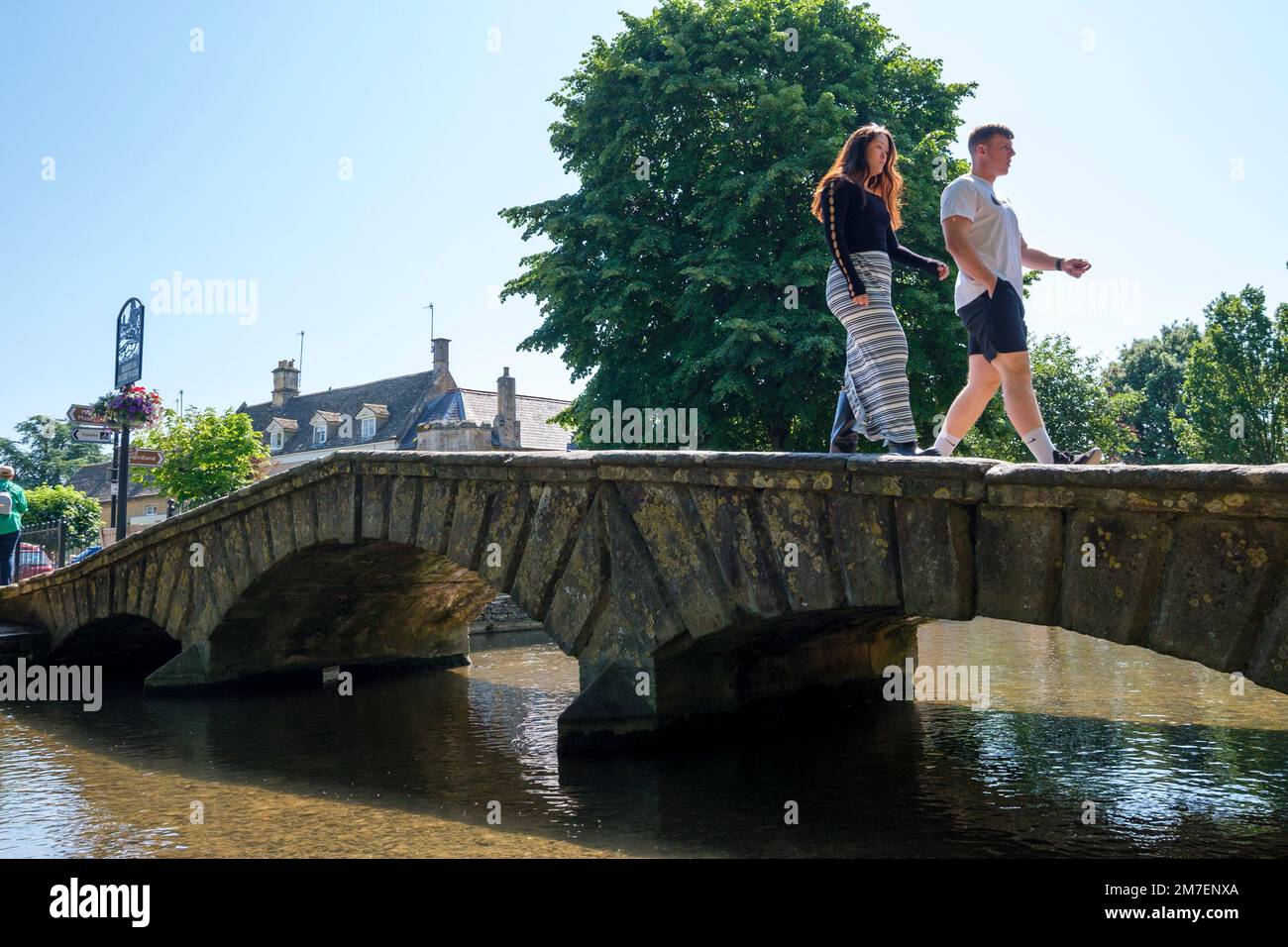 Bourton on the Water, Regno Unito. Le persone amano passeggiare lungo il fiume, scattare foto e godersi il caldo clima estivo a Bourton sull'acqua Foto Stock
