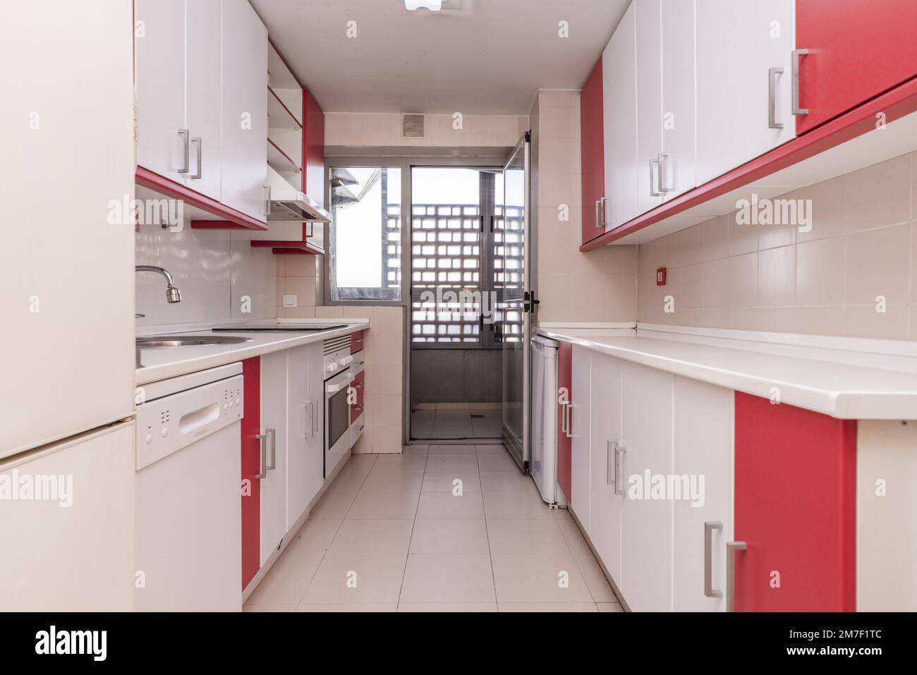 cucina di una casa al piano terra con accesso ad una terrazza con mobili bicolore, ripiani bianchi e elettrodomestici bianchi integrati Foto Stock