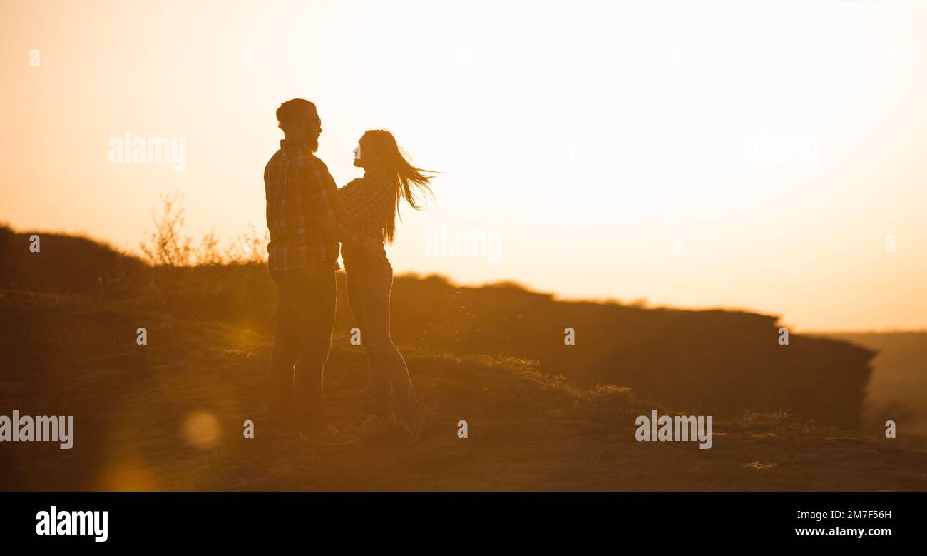 L'uomo bearato e la donna dai capelli rossi stanno abbracciando al tramonto. Foto Stock