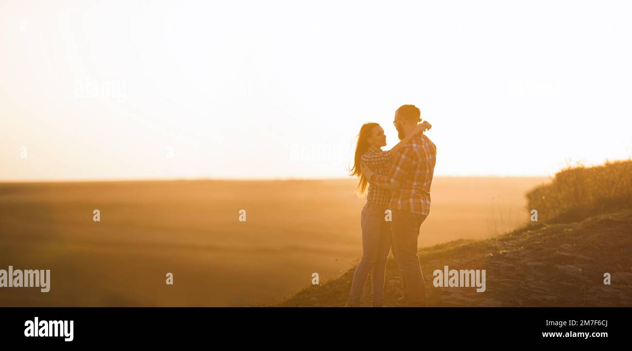 L'uomo bearato e la donna dai capelli rossi stanno abbracciando al tramonto. Foto Stock