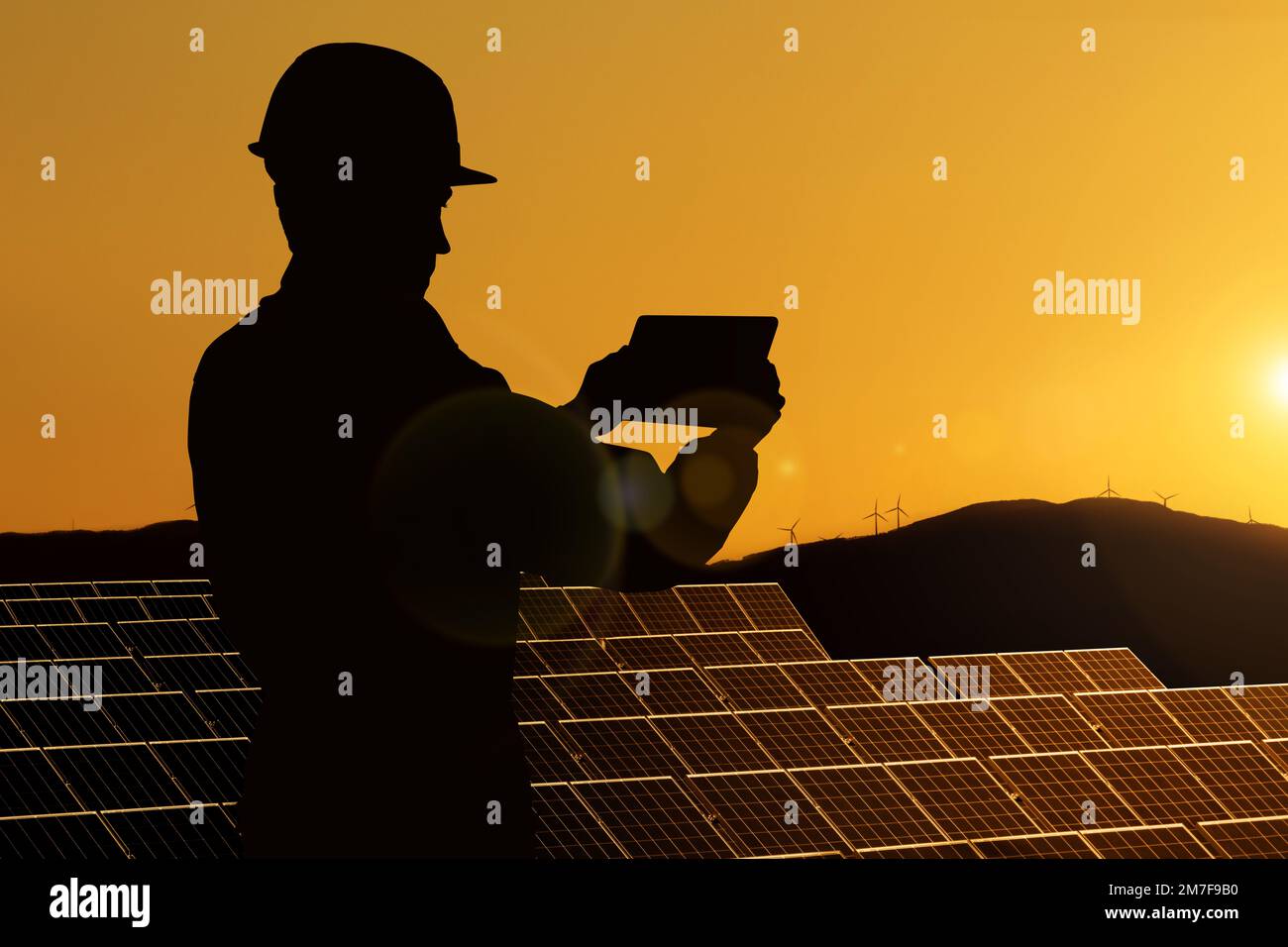 Silhouette di ingegnere con computer tablet sullo sfondo di una centrale di energia solare Foto Stock