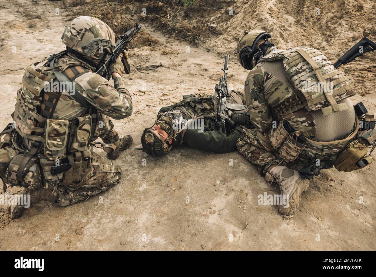 Uomo ferito sdraiato su un terreno, un altro soldato accanto a lui Foto Stock