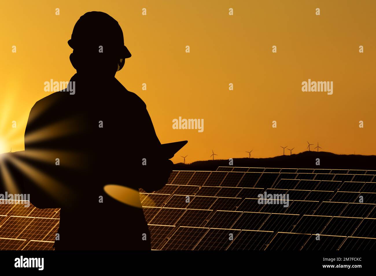 Silhouette di ingegnere con computer tablet sullo sfondo di una centrale di energia solare Foto Stock