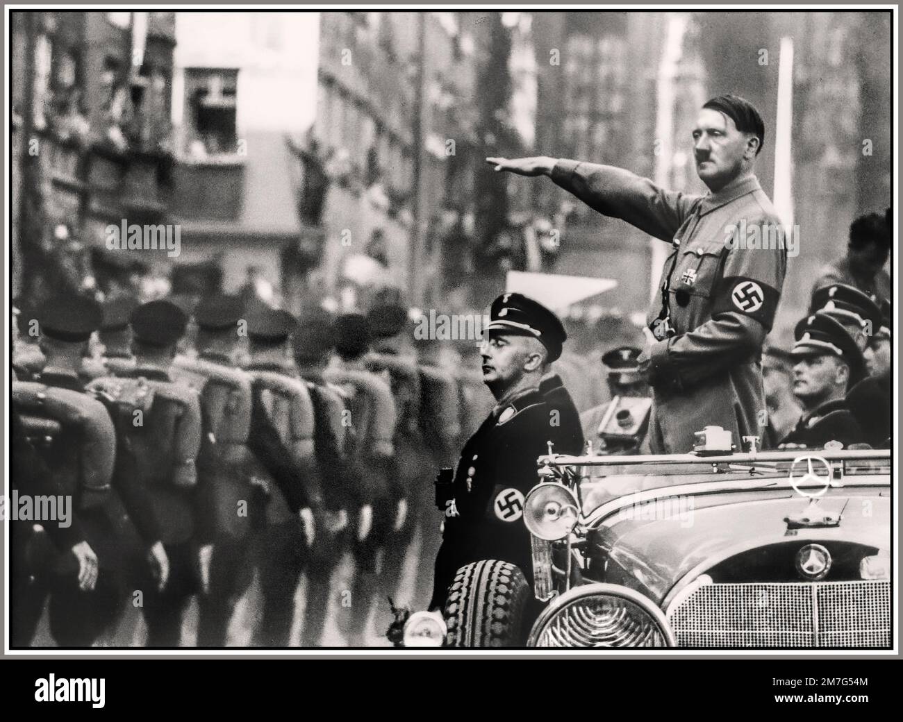 Adolf Hitler dà un saluto a Heil Hitler indossando l'uniforme SA con la fascia da braccio Swastika, in piedi in una Mercedes scoperto circondata da ufficiali Waffen SS, Norimberga Germania nazista 1930s Norimberga SA Rally 1930s con Adolf Hitler in piedi nella sua Mercedes-Benz 770 rivedendo i membri SA (Sturmabteilung) in una parata durante il raduno di Norimberga 1935, Il 7th° Congresso del Partito nazista si è tenuto a Norimberga, dal 10 al 16 settembre. Foto Stock