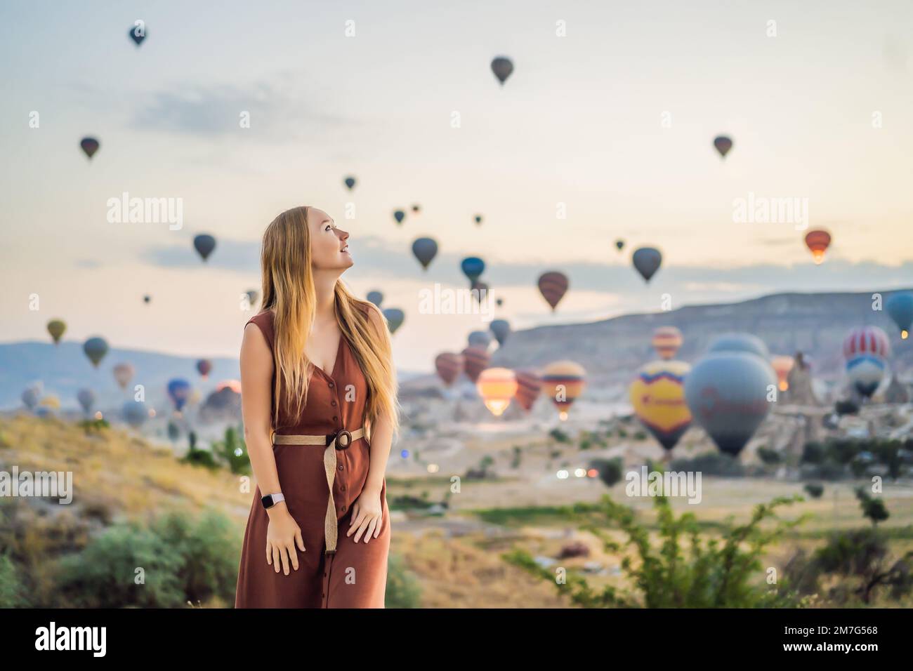 Donna turistica che guarda mongolfiere in Cappadocia, Turchia. Buon viaggio in Turchia concetto. Donna in cima a una montagna che gode di una vista meravigliosa Foto Stock