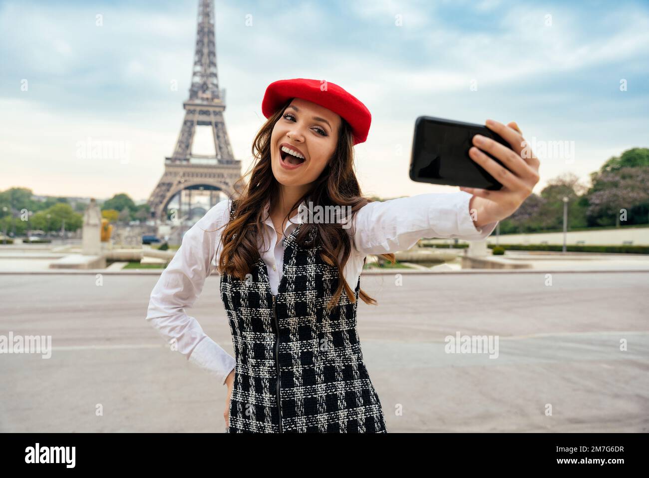 Bella giovane donna in visita a parigi e alla Torre eiffel. Ragazza parigina con cappello rosso e abiti alla moda che si divertono nel centro della città e in landma Foto Stock