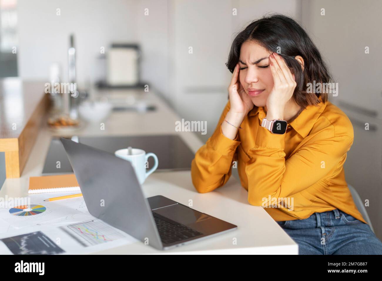 Ritratto di stressata giovane donna araba che ha mal di testa mentre lavora con il laptop Foto Stock