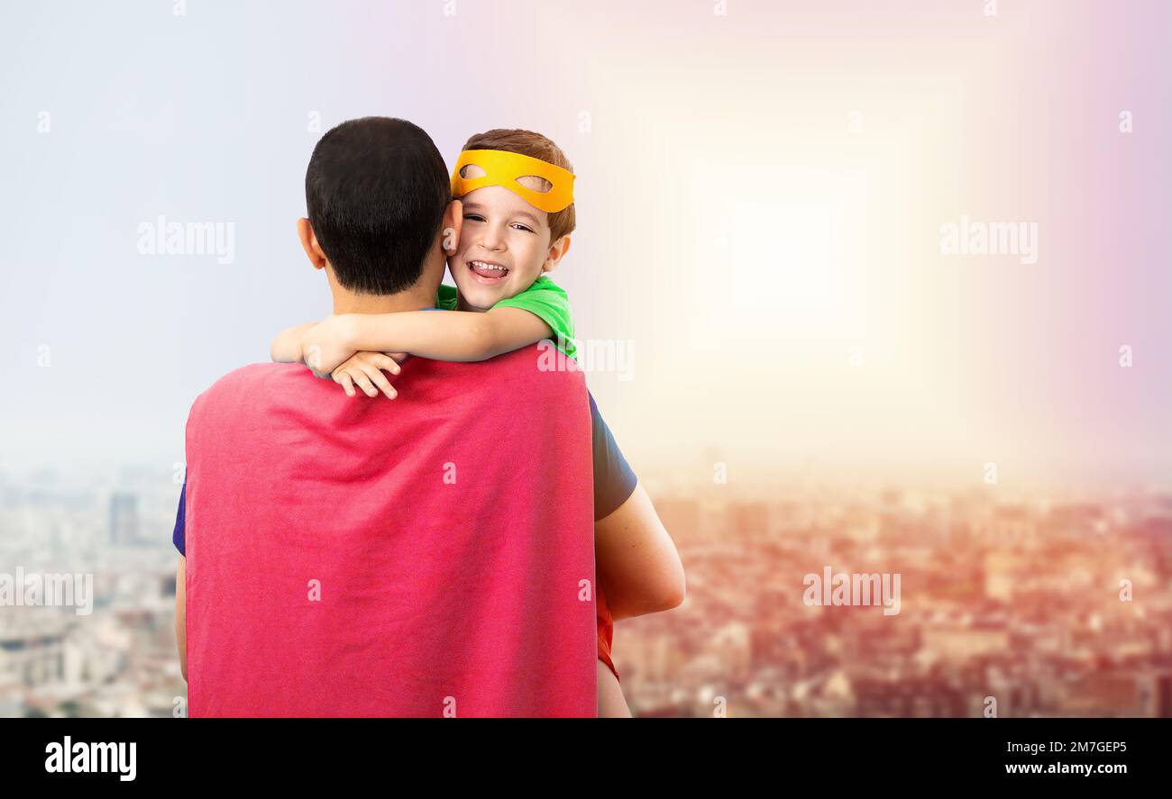 Il mio bellissimo super papà. Affettuoso bambino coccola il padre con amore, indossa una maschera arancione, vestita con costumi supereroi, fiducioso in difesa e papà Foto Stock