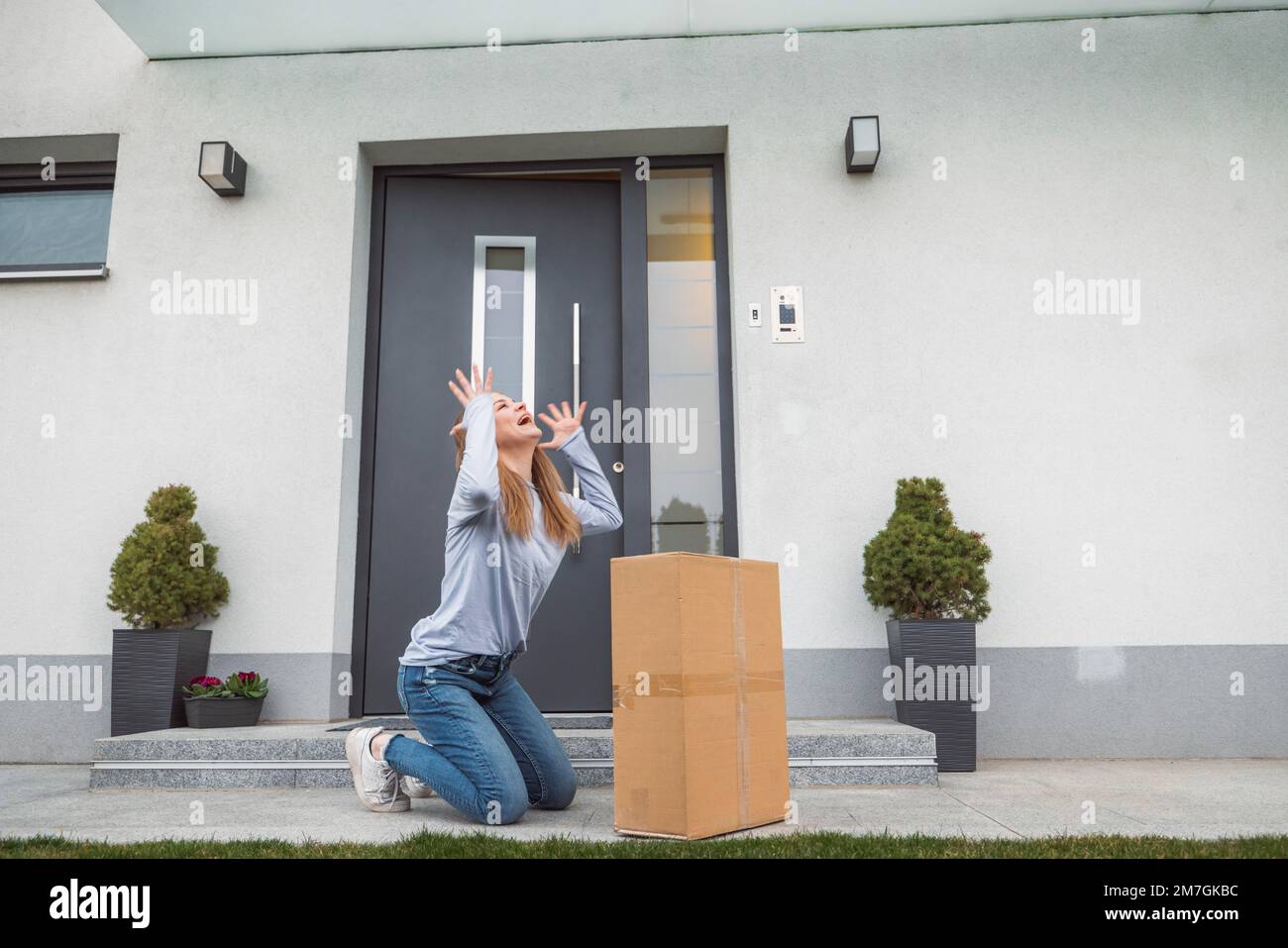 Donna giù alle sue ginocchia che piange dalla felicità, perché finalmente ha ottenuto il lungo pacchetto atteso che ha ordinato un po 'di tempo fa Foto Stock