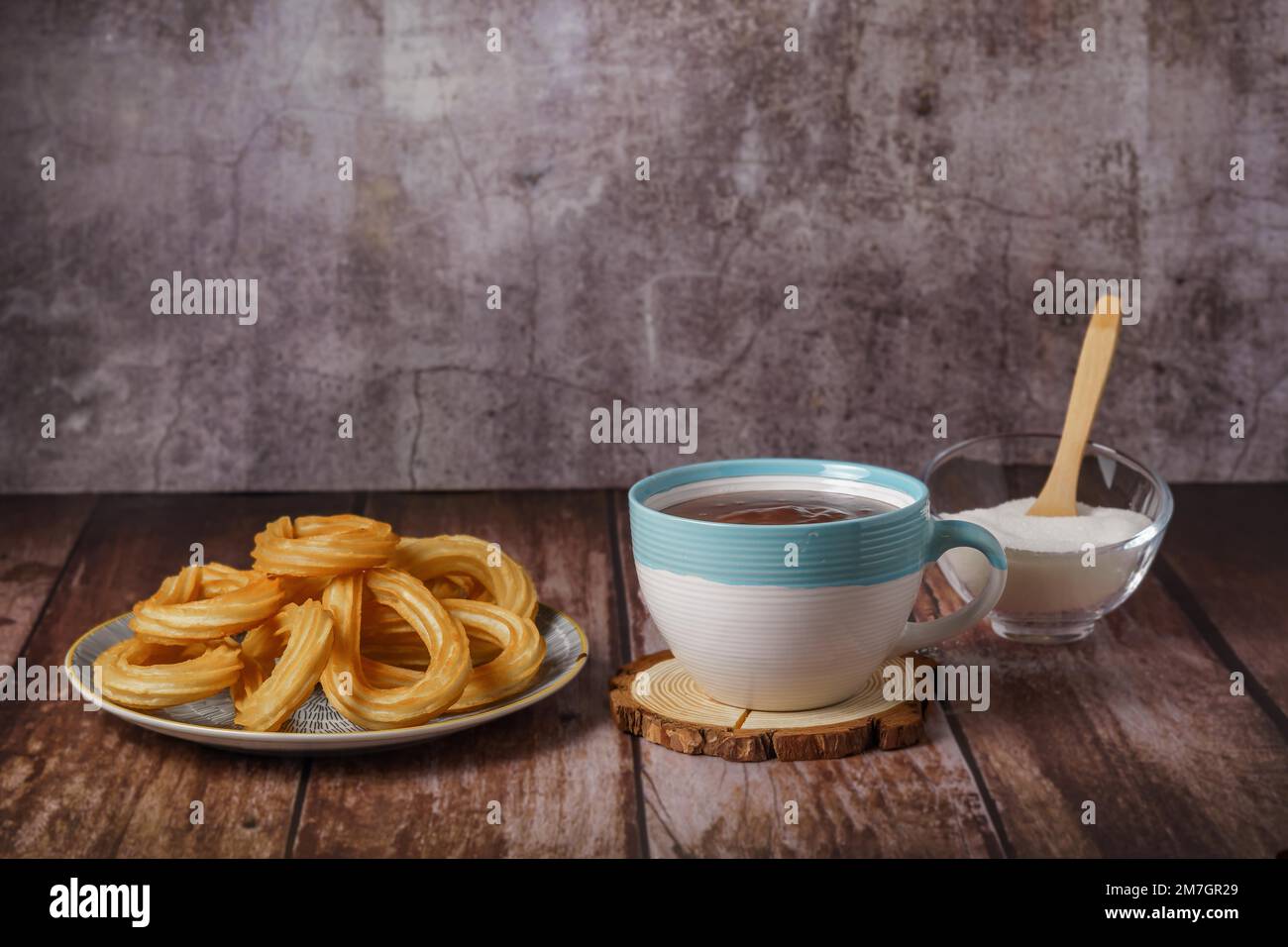 Cioccolata calda con churros in una tazza bianca e blu, tipica colazione spagnola su un tavolo di legno Foto Stock