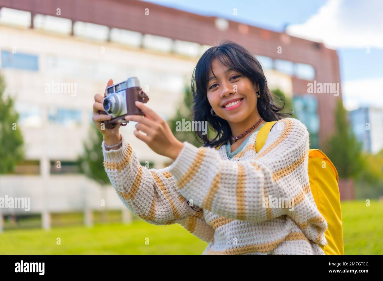 Fotografia asiatica giovane donna con una fotocamera vintage in visita di un parco cittadino, zaino in spalla concetto di viaggiatore Foto Stock