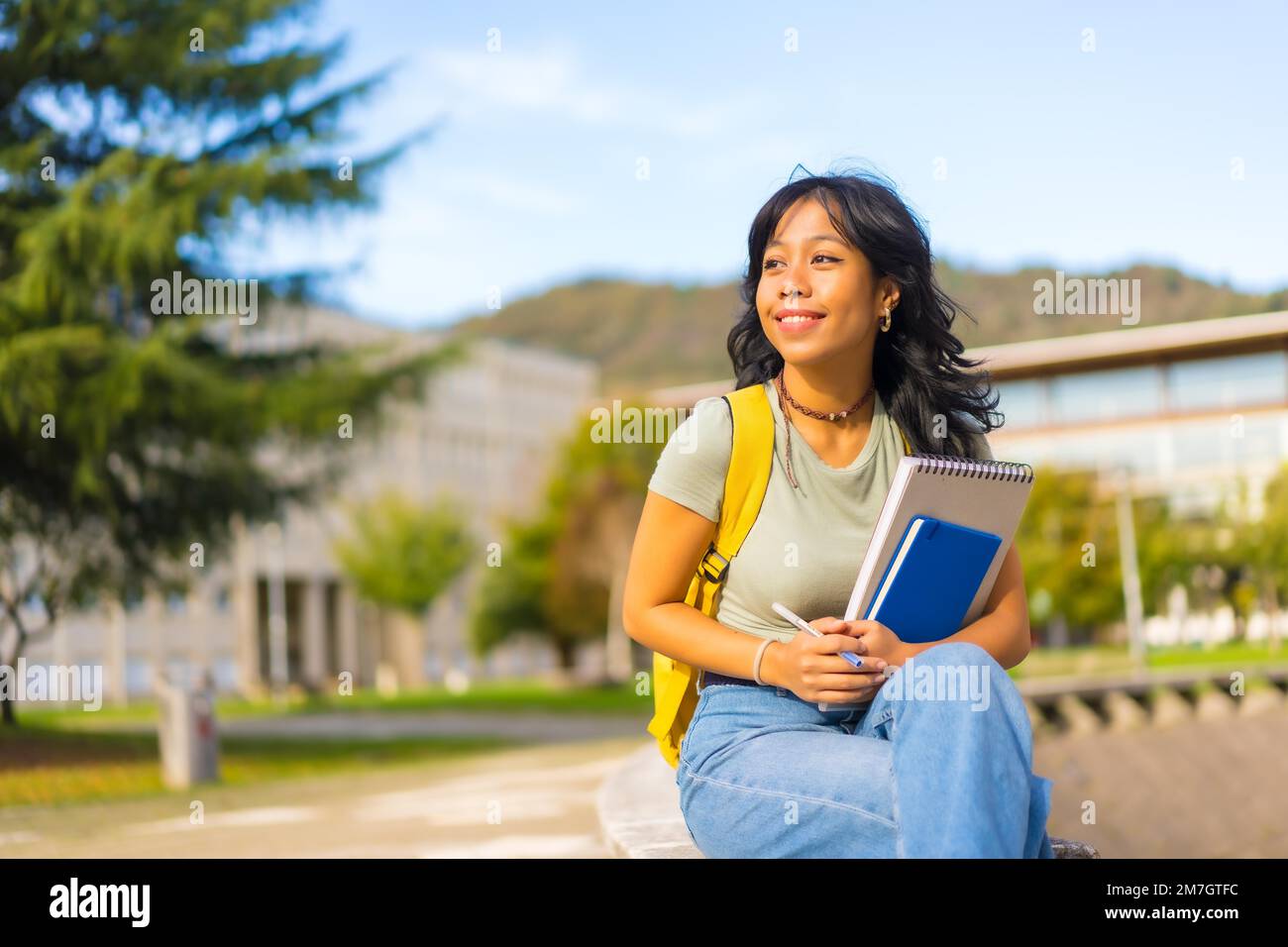 Ragazza asiatica nel campus, studente con blocchi in mano e zaino, sorridente all'università Foto Stock
