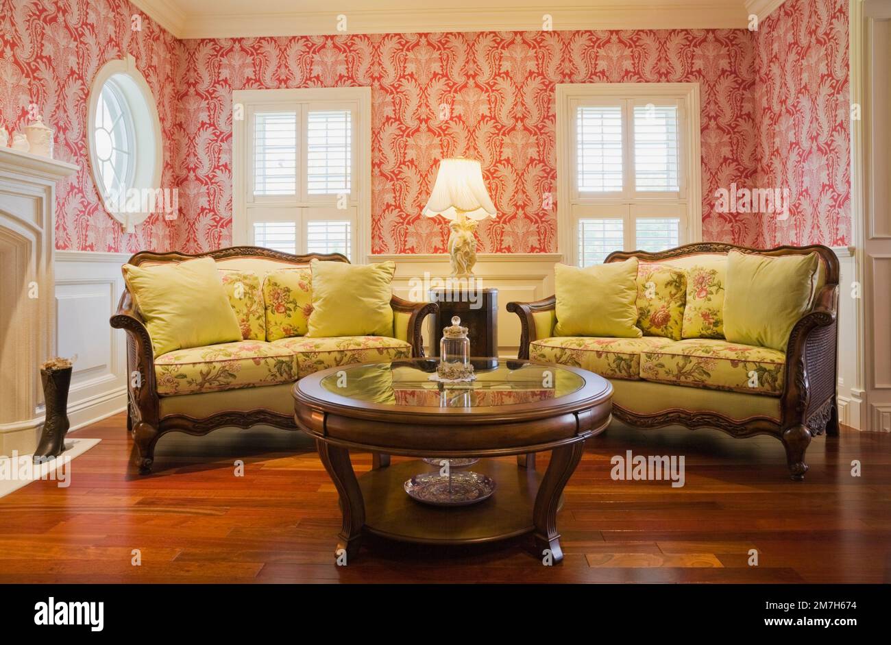 Tavolino da caffè rotondo in legno e divani ricoperti di fiori gialli nella sala salotto all'interno di un'elegante casa in stile cottage. Foto Stock