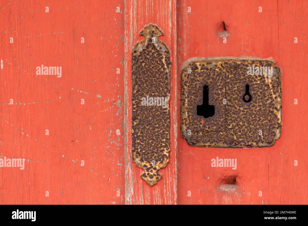 Primo piano di antico buco arrugginito e serratura sulla porta di legno rosso Foto Stock
