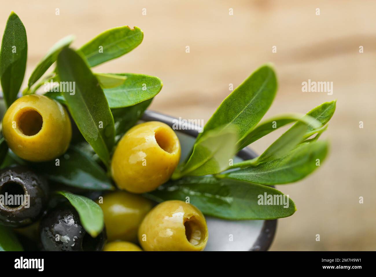 Olive nere e verdi e un ramo di olive verdi in olio d'oliva su un tavolo di legno. Olive e olio d'oliva. Ingrediente della cucina mediterranea Foto Stock