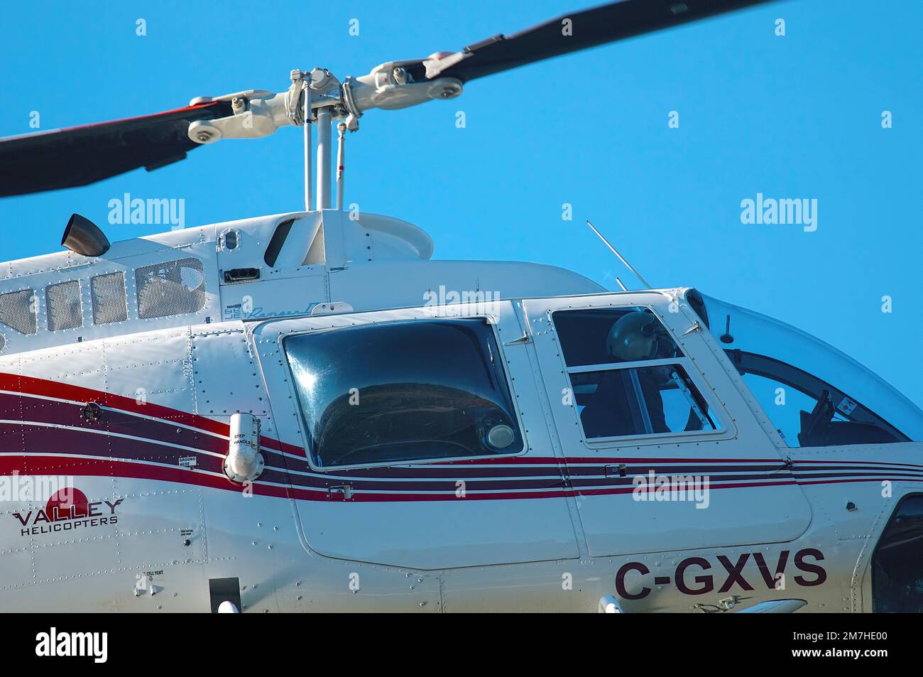 Vista in primo piano di un elicottero bianco e rosso con pilota mentre vola. Metro Vancouver, British Columbia, Canada. Foto Stock