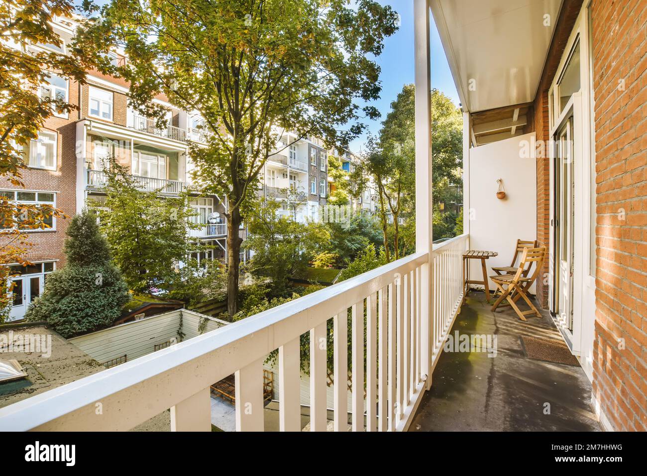 una zona esterna con alberi e case sullo sfondo, come visto da un balcone in una giornata di sole estate Foto Stock