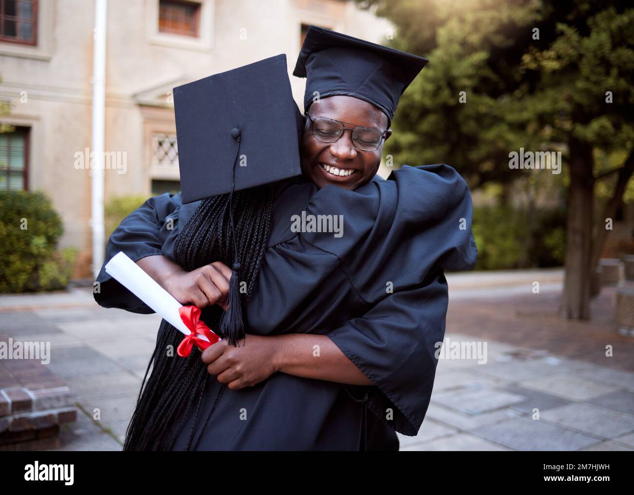 Gente nera, abbraccio e celebrazione nella cerimonia di laurea, successo di laurea o obiettivi di diploma scolastico. Sorridere, amici felici e laurearsi Foto Stock