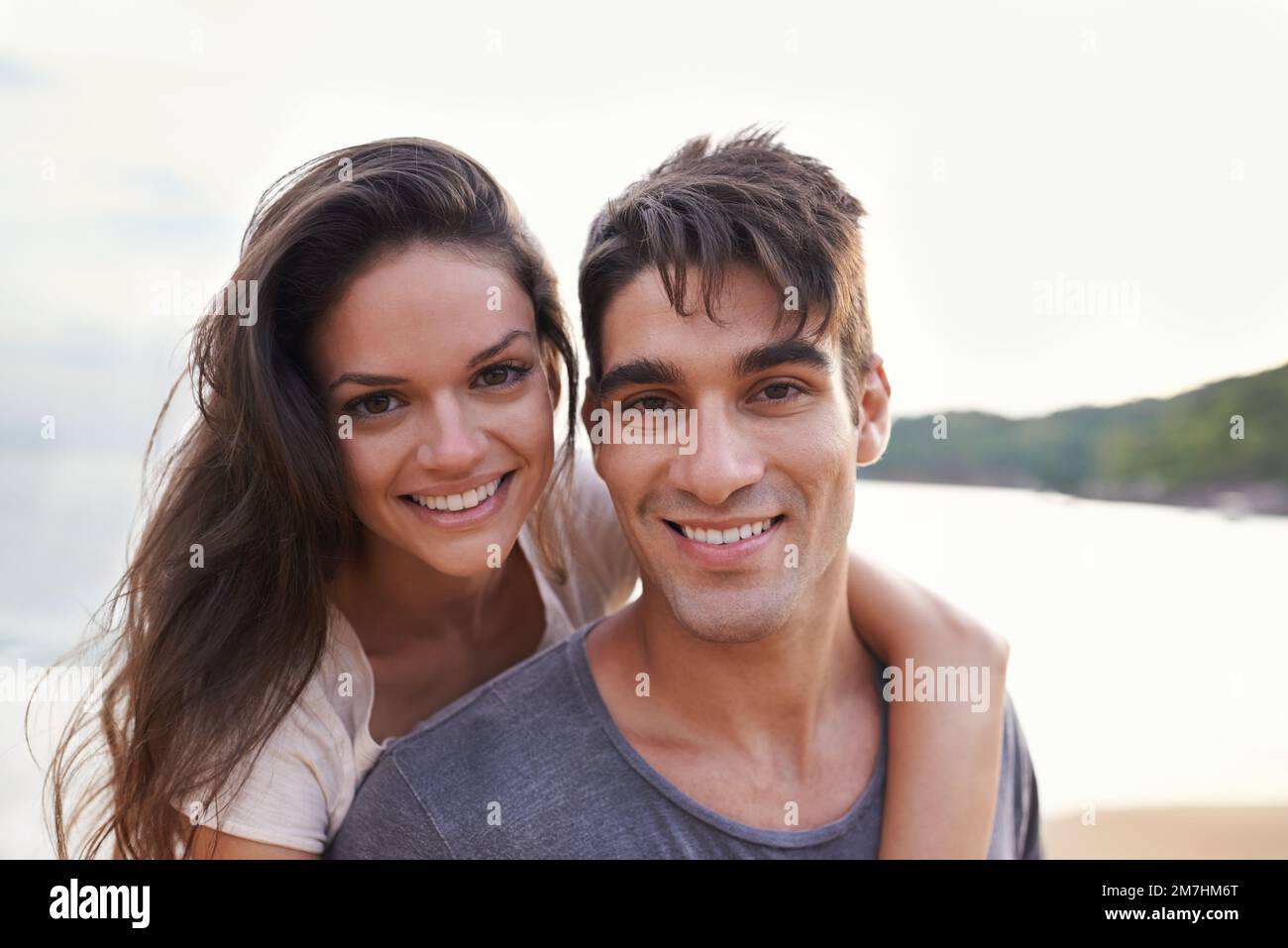 Inseparabile. Un tiro corto di un giovane che dà alla sua ragazza un giro in piggyback sulla spiaggia. Foto Stock