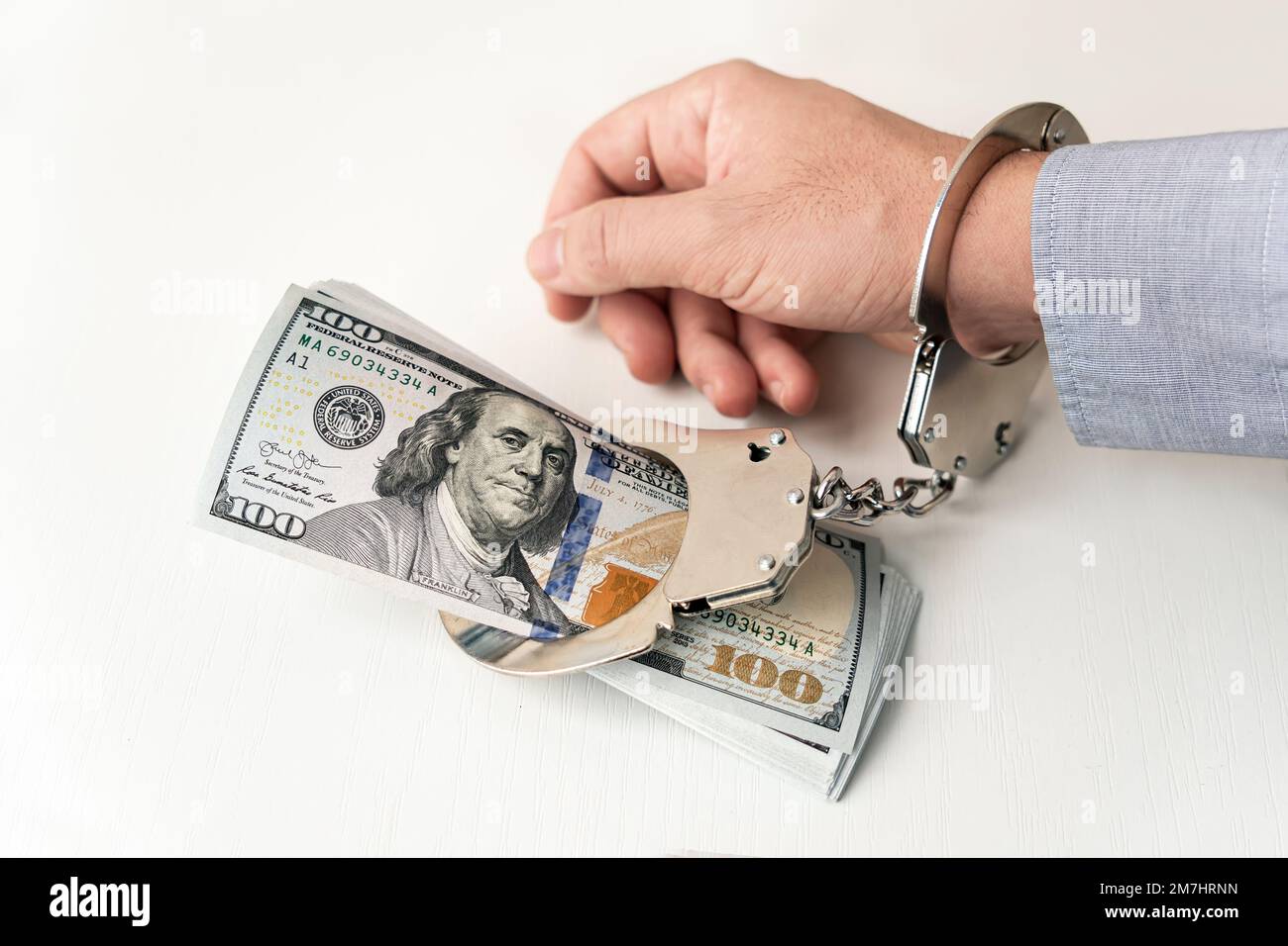 Mano con manette e dollari USA su sfondo bianco. concetto di dipendenza dal denaro. La criminalità in ambito finanziario. uomo d'affari criminale, corrotto Foto Stock
