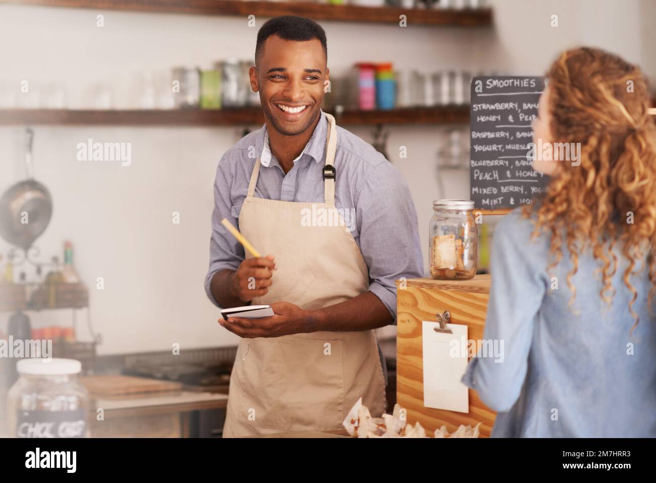 Che cosa posso ottenere per voi oggi. giovane barista che effettua un ordine presso un bar. Foto Stock