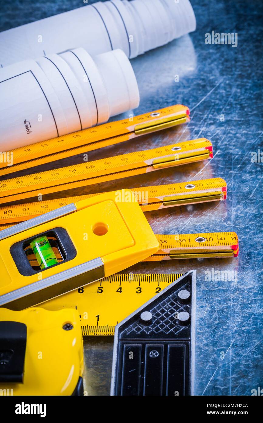 Primo piano di progetti a livello di costruzione e strumenti di misurazione sul concetto di architettura e costruzione di superfici graffiate metalliche. Foto Stock