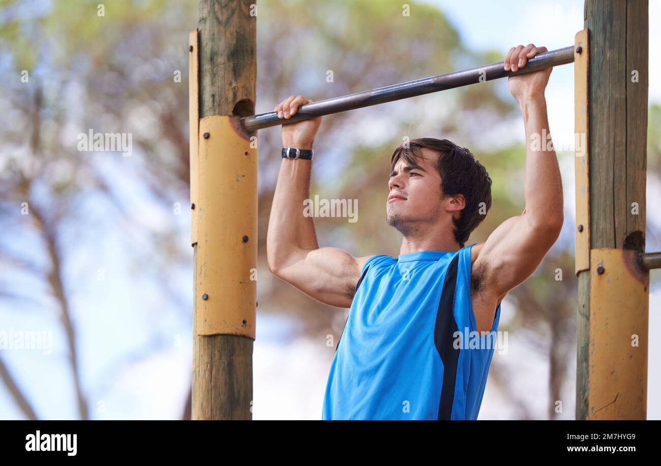 La determinazione è tutto. Giovane adulto maschio usando l'apparecchiatura esterna della palestra. Foto Stock