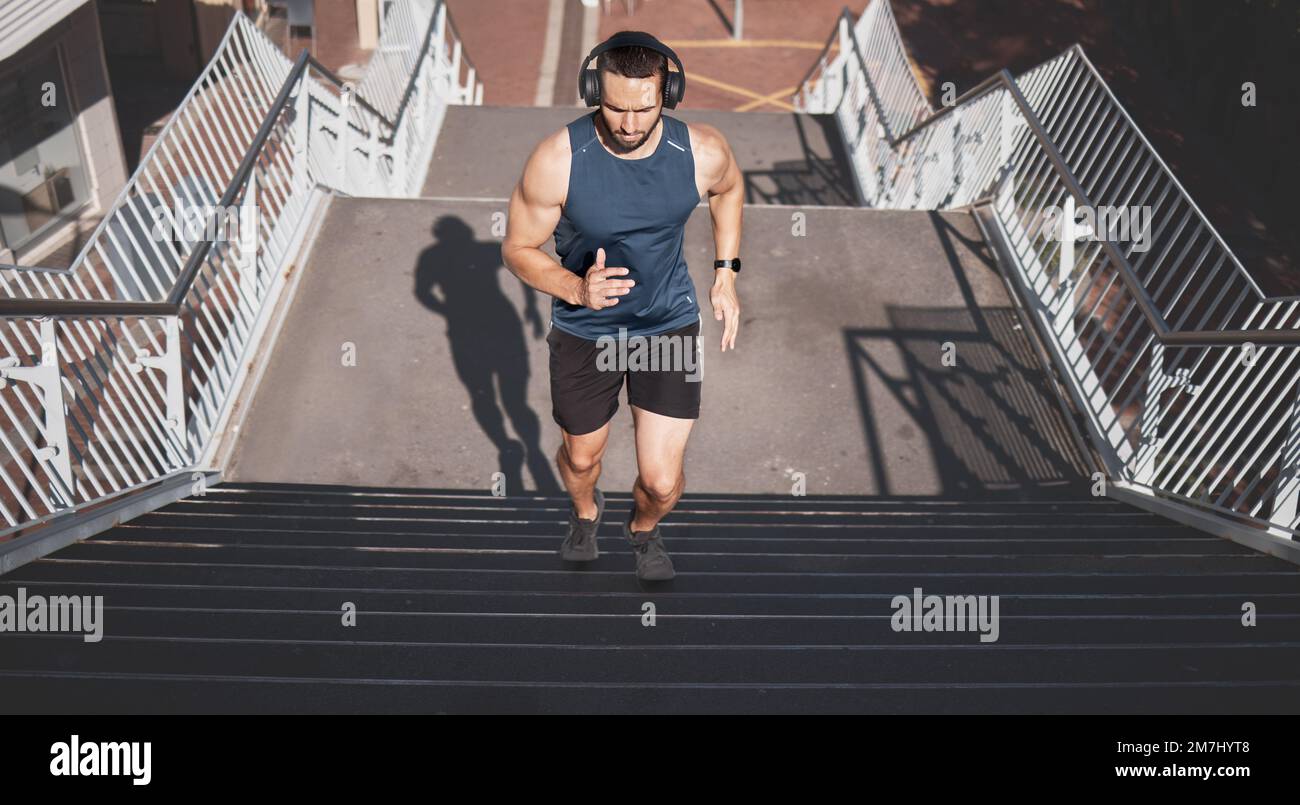 Urban fitness, uomo che corre sulle scale e ascolta musica con le cuffie durante gli esercizi all'aperto a Los Angeles. Salute, motivazione e una città della California Foto Stock
