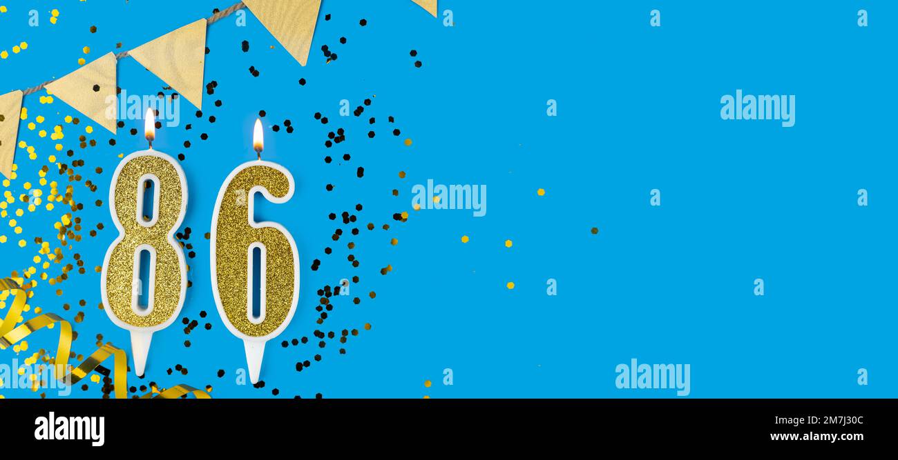 Candela d'oro numero ottantasei. Cartellino di compleanno o anniversario con l'iscrizione 86 su sfondo blu. Celebrazione dell'anniversario. Banner. Foto Stock