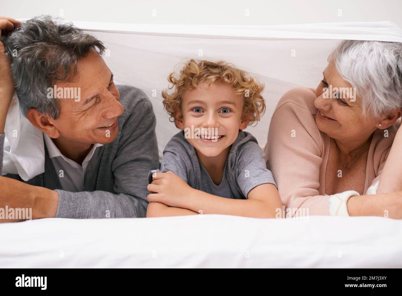 Antics sottocopertino. Un ragazzo che si diverte con i nonni. Foto Stock