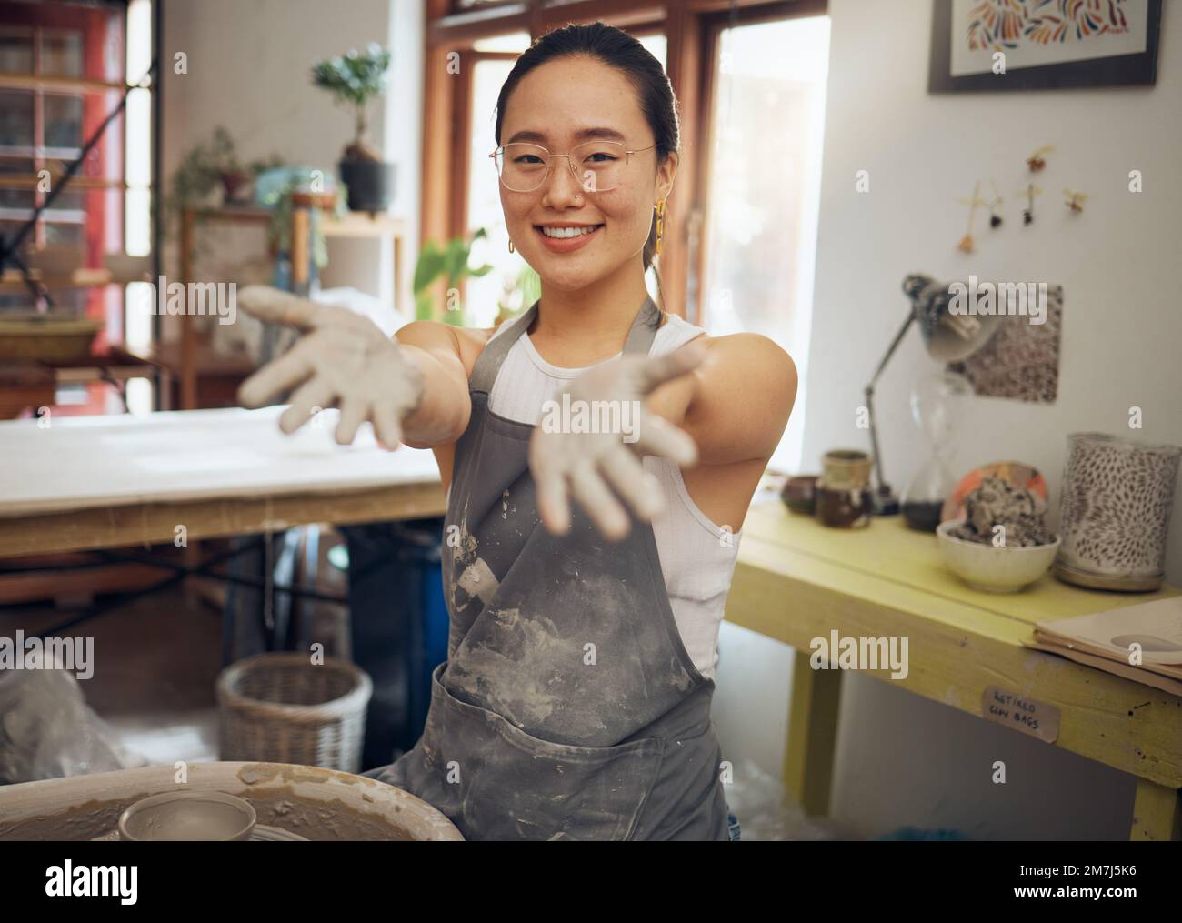 Ritratto, ceramica di argilla e donna asiatica in studio, sorriso e scultura per il business, design art o creativo. Mani, imprenditrice o artista Foto Stock