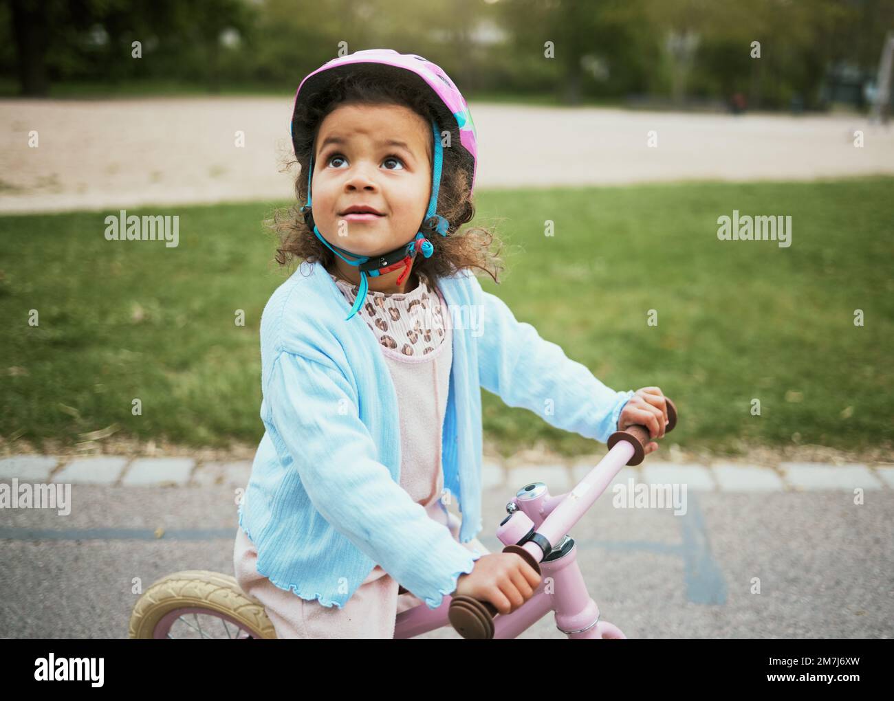 Ciclismo, divertimento e bambini in bicicletta nel parco, attività all'aperto e apprendimento in Nuova Zelanda. porto, felicità e ragazza bambino che gioca in bicicletta Foto Stock