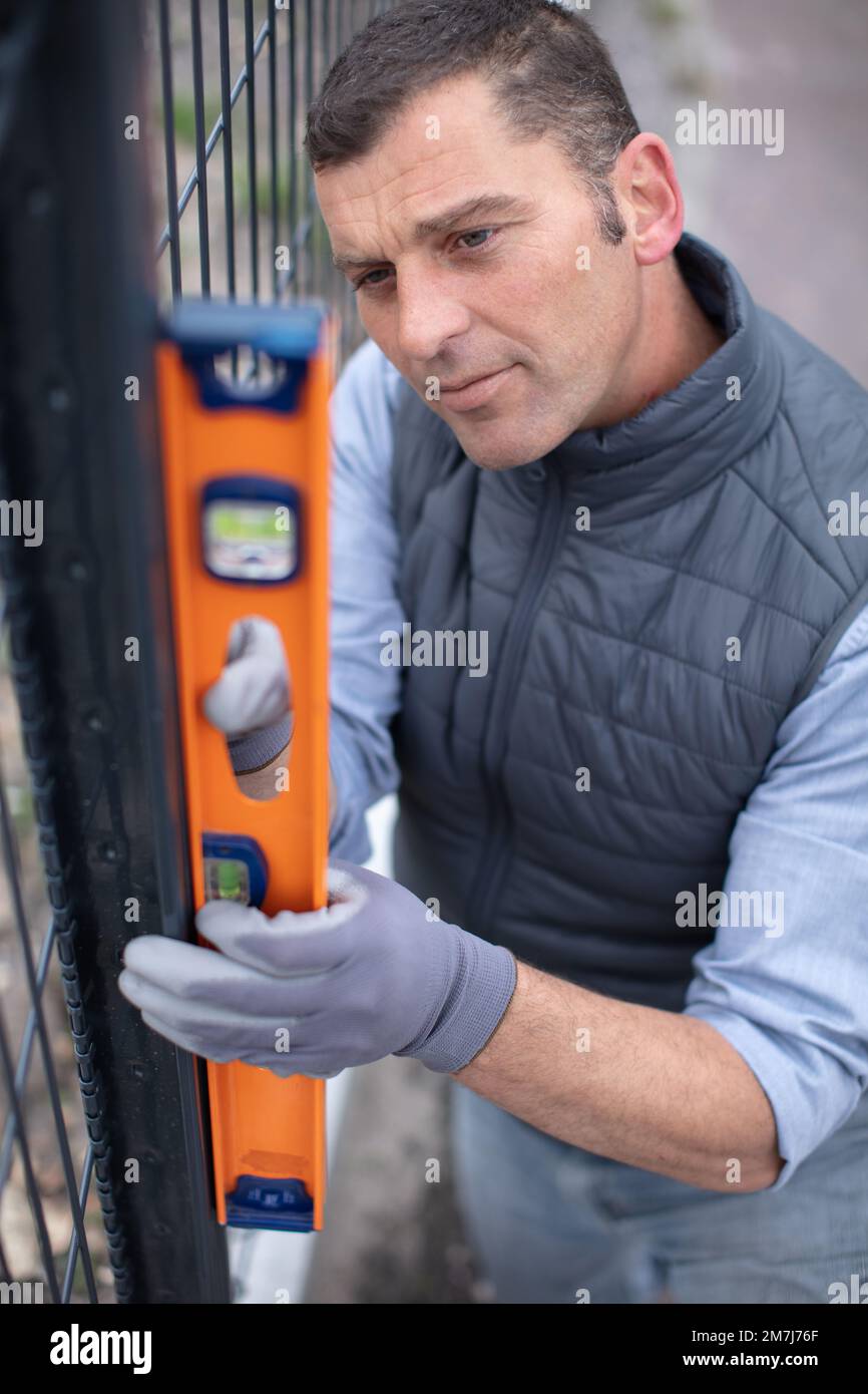 un lavoratore controlla il livello di recinzione di metallo Foto Stock