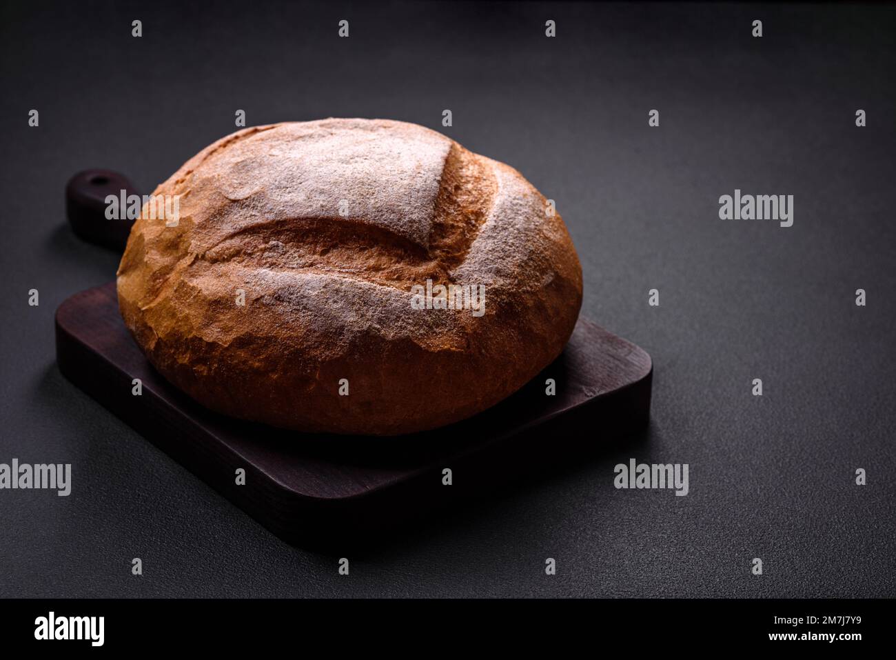 Delizioso pane bianco di forma rotonda appena sfornato su uno sfondo di  cemento scuro Foto stock - Alamy