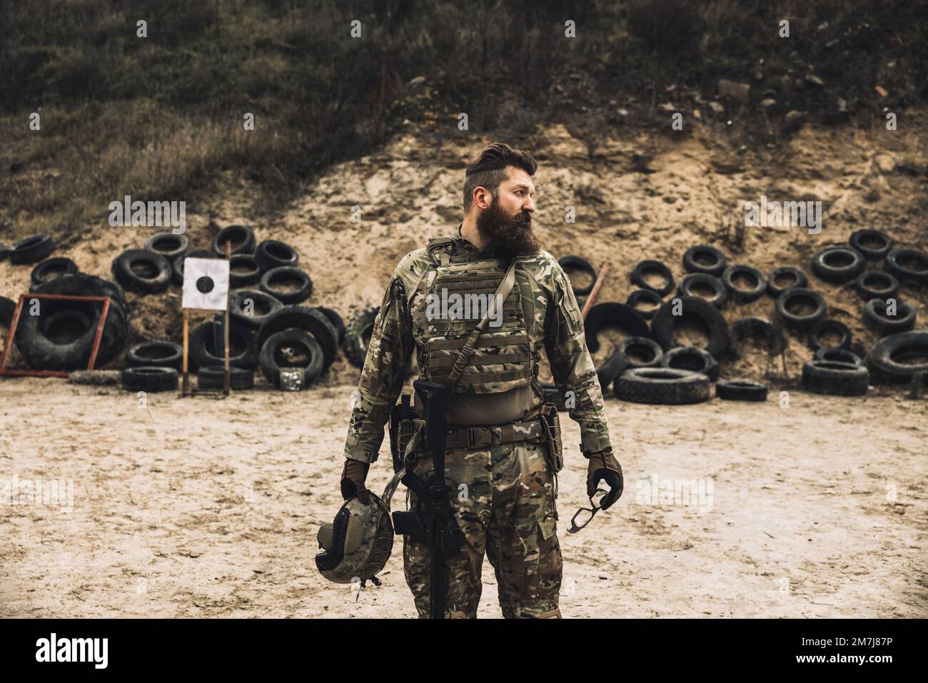 Uomo bearded dai capelli scuri in uniforme militare che guarda determinato Foto Stock