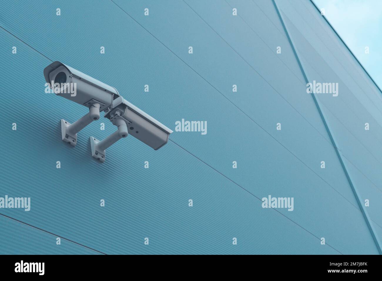 Telecamera di sicurezza per sorveglianza esterna montata sulla parete di un edificio industriale per monitorare l'attività al di fuori dei locali Foto Stock