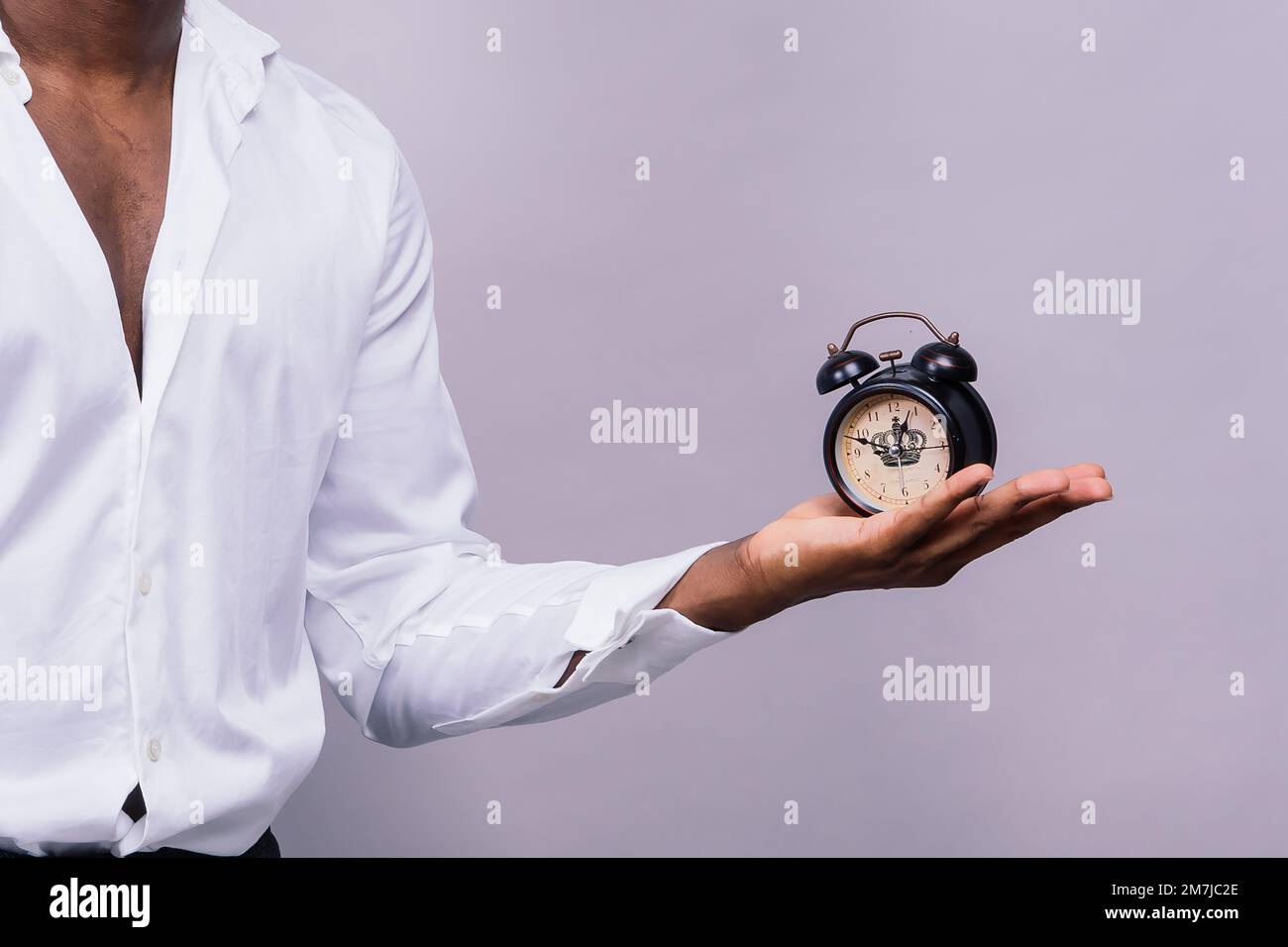 Concetto di gestione del tempo. Uomo nero scioccato che tiene orologio da parete, in esaurimento. Foto Stock